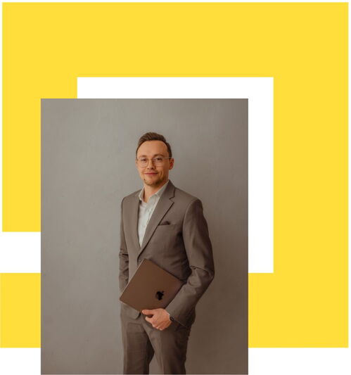 Porträt eines jungen Geschäftsmannes mit Brille und braunem Anzug: Er steht vor einem neutralen grauen Hintergrund, hält einen Laptop in der Hand und lächelt selbstbewusst. Im Hintergrund befindet sich ein gelbes, grafisches Designelement mit weissen und